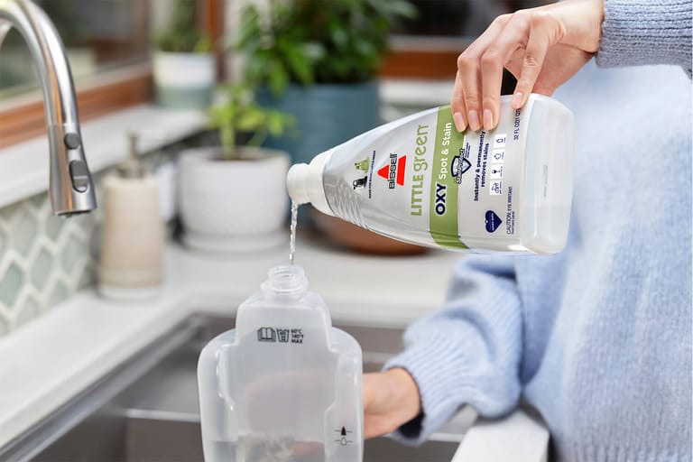 BISSELL Little Green OXY Spot and Stain formula being poured into a detached solution tank.